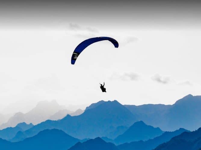 Person gliding between mountains with a parachute