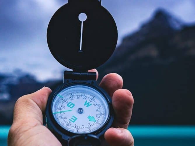 hand-holding-compass A hand holding a compass in front of a beautiful view